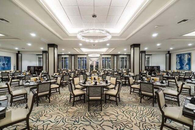 dining space with visible vents, decorative columns, a tray ceiling, and ornamental molding