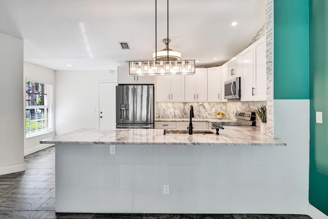 kitchen with tasteful backsplash, visible vents, appliances with stainless steel finishes, light stone counters, and a sink