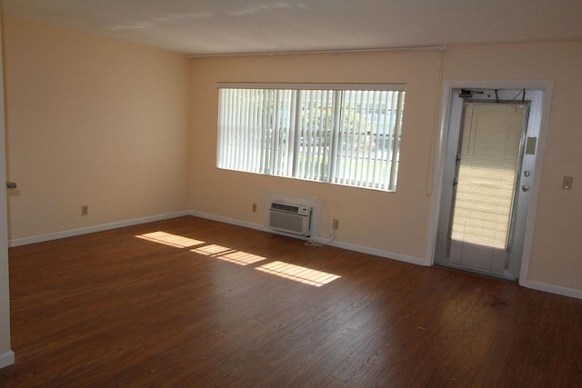 empty room with dark wood-style floors, baseboards, and an AC wall unit