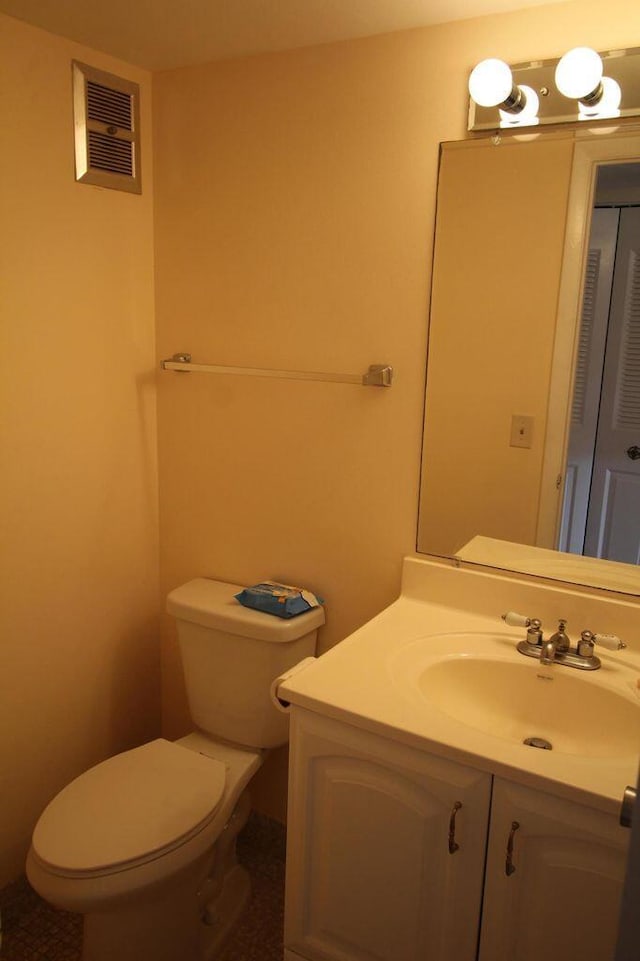 half bathroom featuring toilet, a closet, vanity, and visible vents