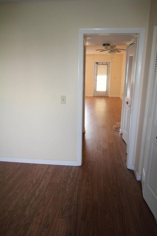 hallway featuring baseboards and dark wood finished floors