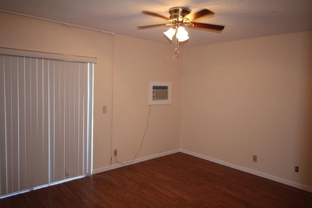 spare room featuring baseboards, a ceiling fan, dark wood-type flooring, a wall mounted air conditioner, and a textured ceiling