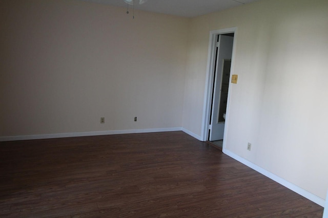 unfurnished room featuring dark wood-type flooring and baseboards