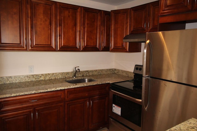 kitchen with reddish brown cabinets, light stone counters, stainless steel appliances, a sink, and ventilation hood