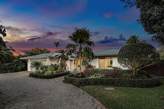 ranch-style house featuring metal roof, a garage, fence, decorative driveway, and stucco siding