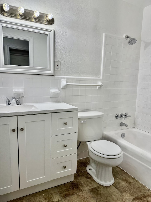 bathroom featuring shower / washtub combination, tile walls, vanity, and toilet