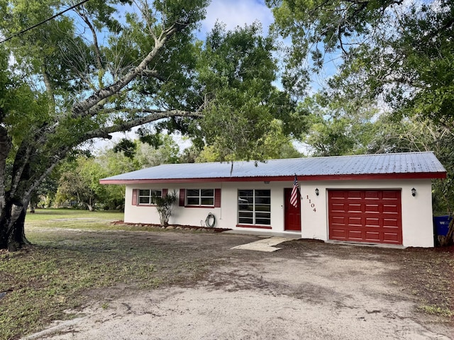 ranch-style home with a garage, metal roof, and stucco siding