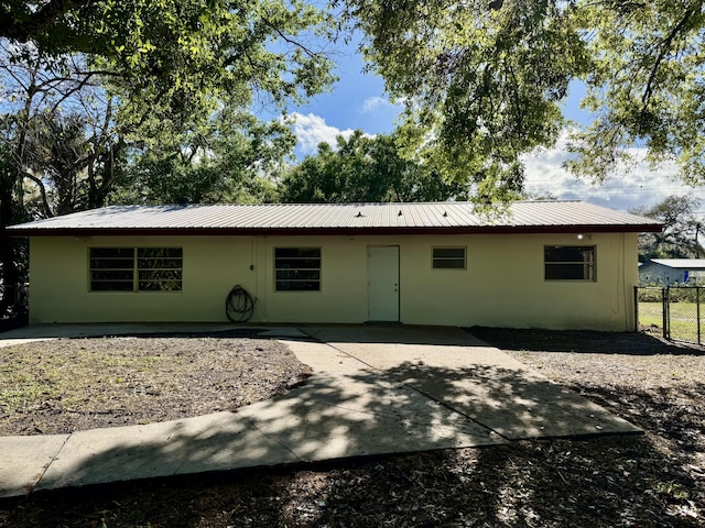 ranch-style house featuring metal roof, a patio, and fence