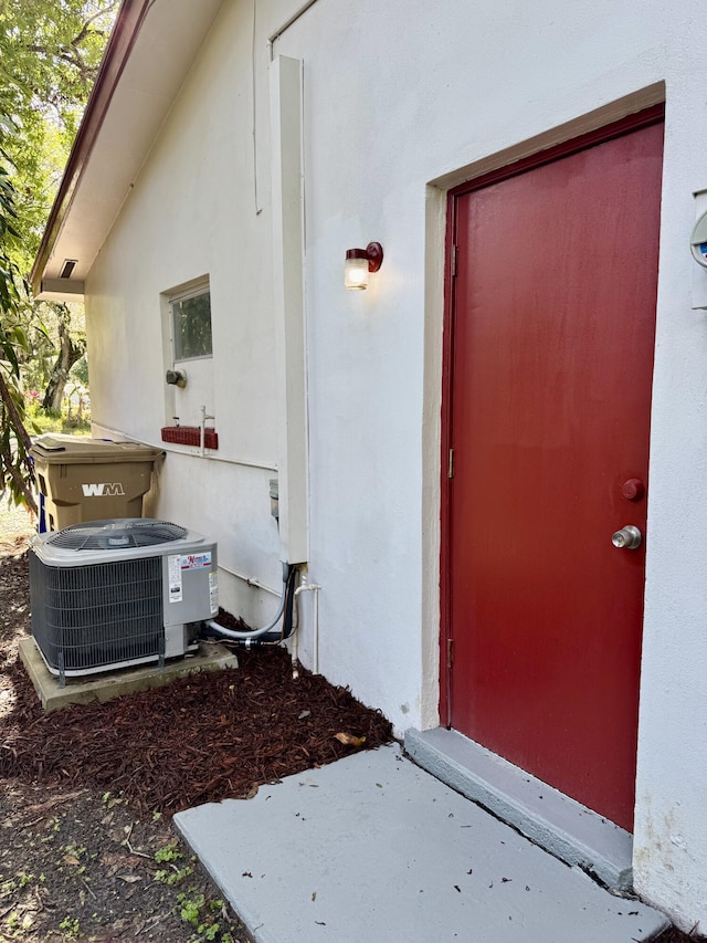 property entrance featuring central air condition unit and stucco siding