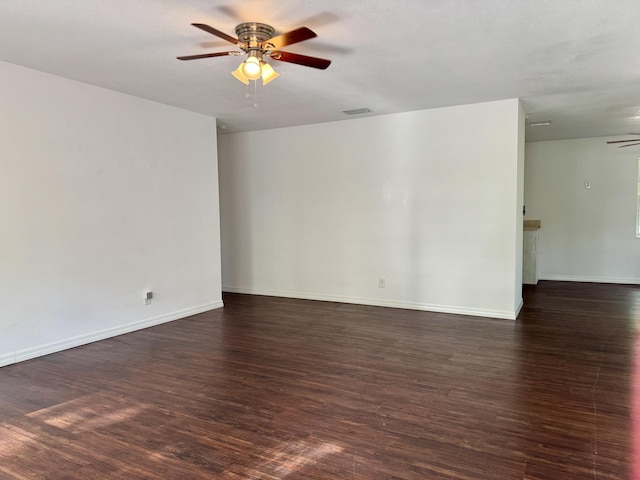 unfurnished room with ceiling fan, wood finished floors, visible vents, and baseboards