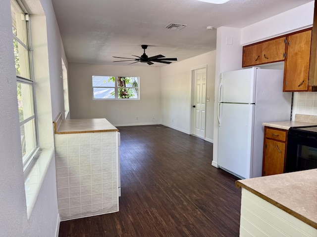 kitchen featuring dark wood-style flooring, brown cabinets, black range with electric stovetop, and visible vents