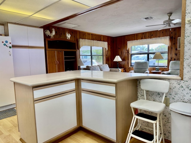 kitchen featuring light wood-style flooring, visible vents, white cabinetry, light countertops, and freestanding refrigerator