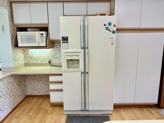 kitchen featuring light wood-style floors, white appliances, white cabinetry, and wallpapered walls