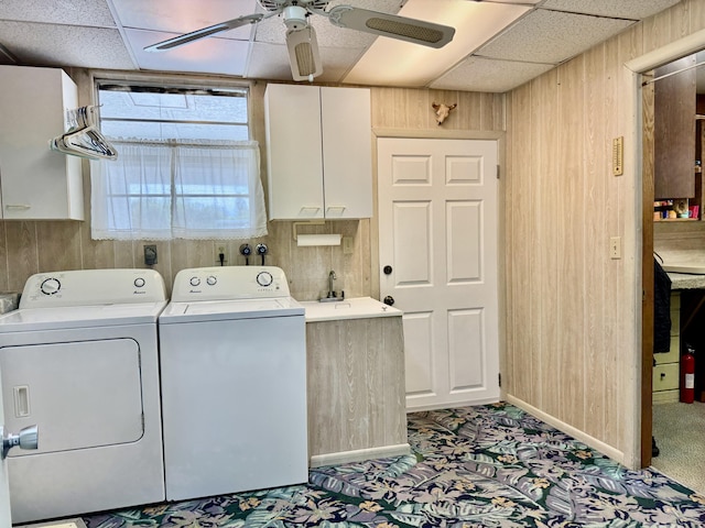 washroom featuring wooden walls, cabinet space, washer and clothes dryer, and a ceiling fan