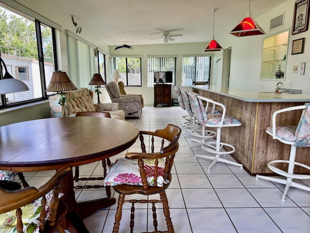 dining area with visible vents, plenty of natural light, a textured ceiling, and light tile patterned floors