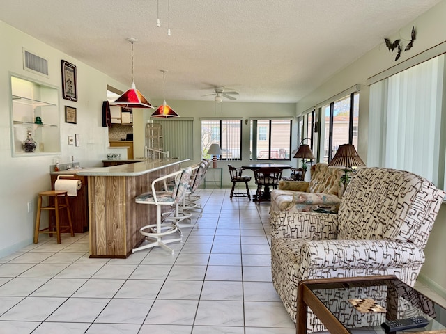 kitchen featuring light countertops, light tile patterned flooring, ceiling fan, a textured ceiling, and a kitchen breakfast bar