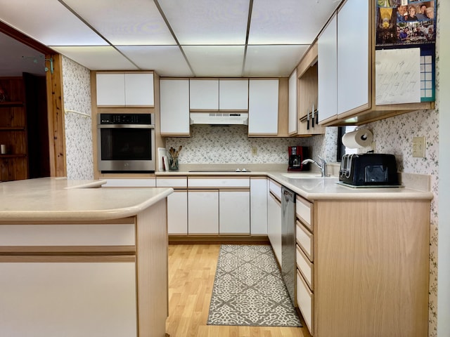 kitchen with stainless steel appliances, light countertops, white cabinets, and under cabinet range hood