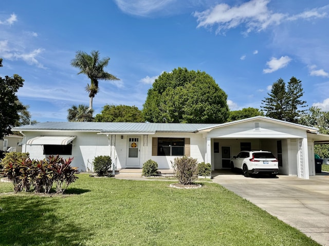 ranch-style house with metal roof, an attached carport, a front lawn, and concrete driveway