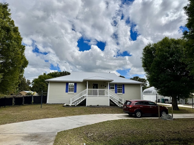 view of front facade featuring a porch, stairway, a front yard, metal roof, and fence