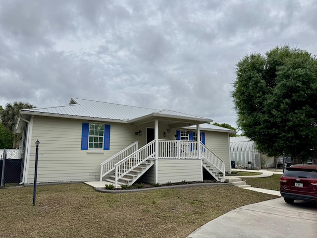 2532 NW 33rd Ave, Okeechobee, FL 34972 - view of front of house featuring metal roof, stairs, a front yard, and a porch