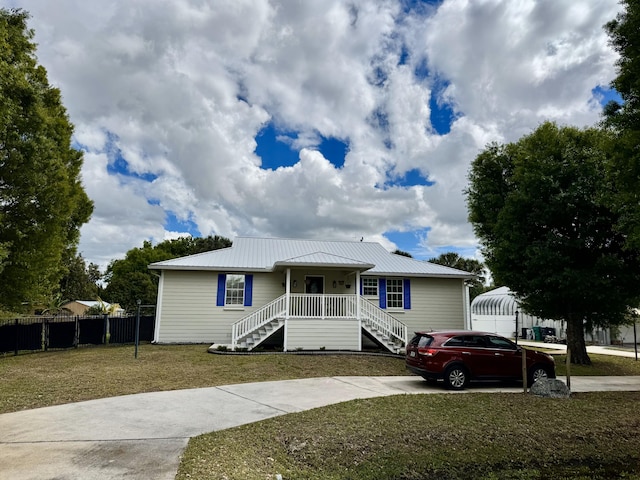 2532 NW 33rd Ave, Okeechobee, FL 34972 - view of front of house with stairs, fence, driveway, metal roof, and a front lawn