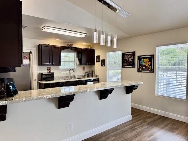 2532 NW 33rd Ave, Okeechobee, FL 34972 - kitchen featuring dark brown cabinets, a sink, a kitchen breakfast bar, dark wood-type flooring, and baseboards