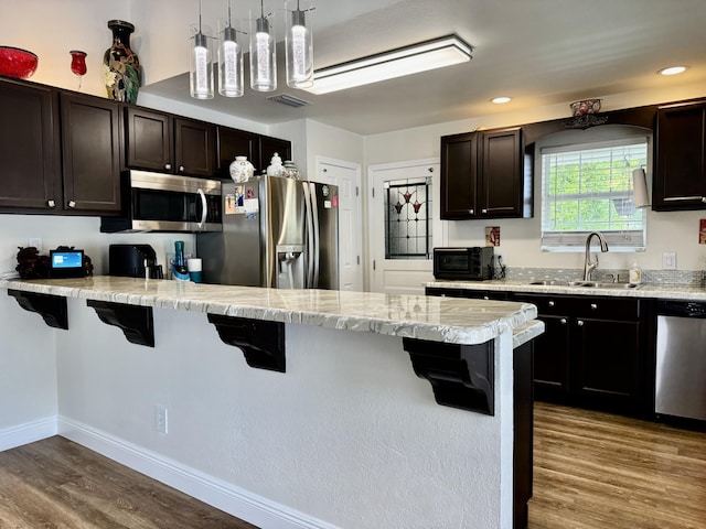 2532 NW 33rd Ave, Okeechobee, FL 34972 - kitchen with a sink, a peninsula, a kitchen breakfast bar, stainless steel appliances, and dark wood-style floors
