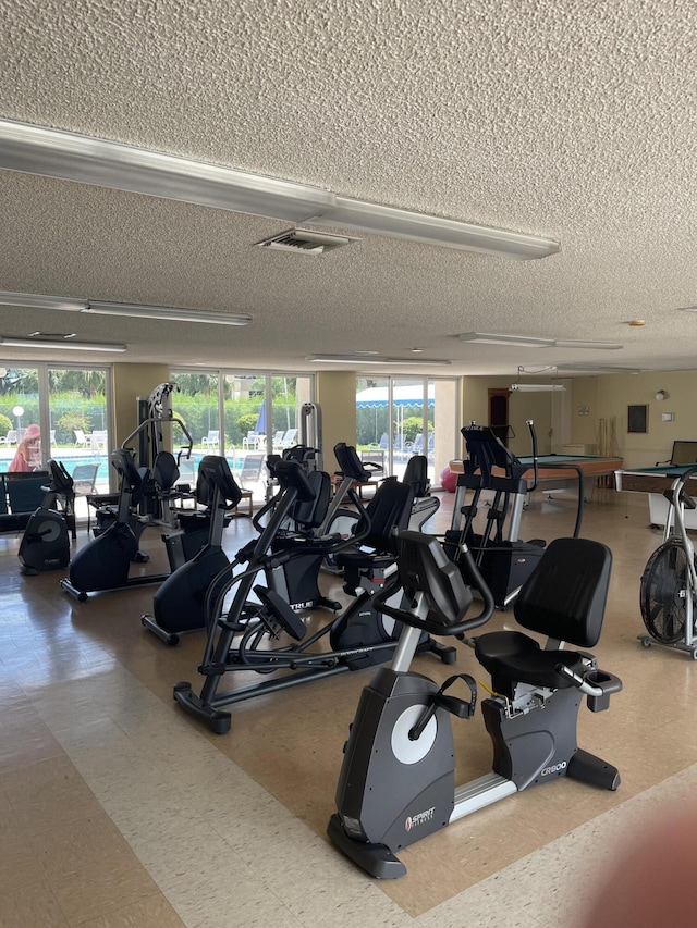 exercise room with a textured ceiling, a wealth of natural light, and tile patterned floors