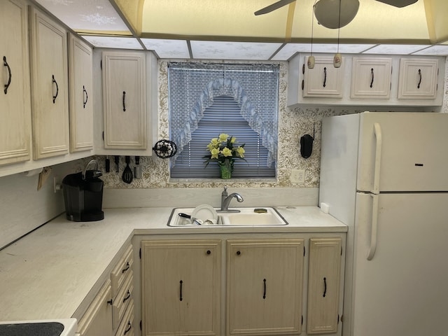 kitchen with a ceiling fan, freestanding refrigerator, light countertops, light brown cabinets, and a sink