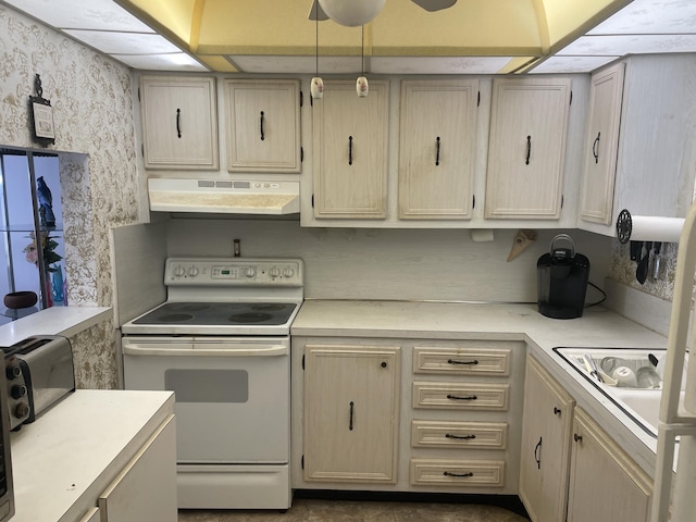 kitchen featuring a toaster, light countertops, electric range, under cabinet range hood, and wallpapered walls