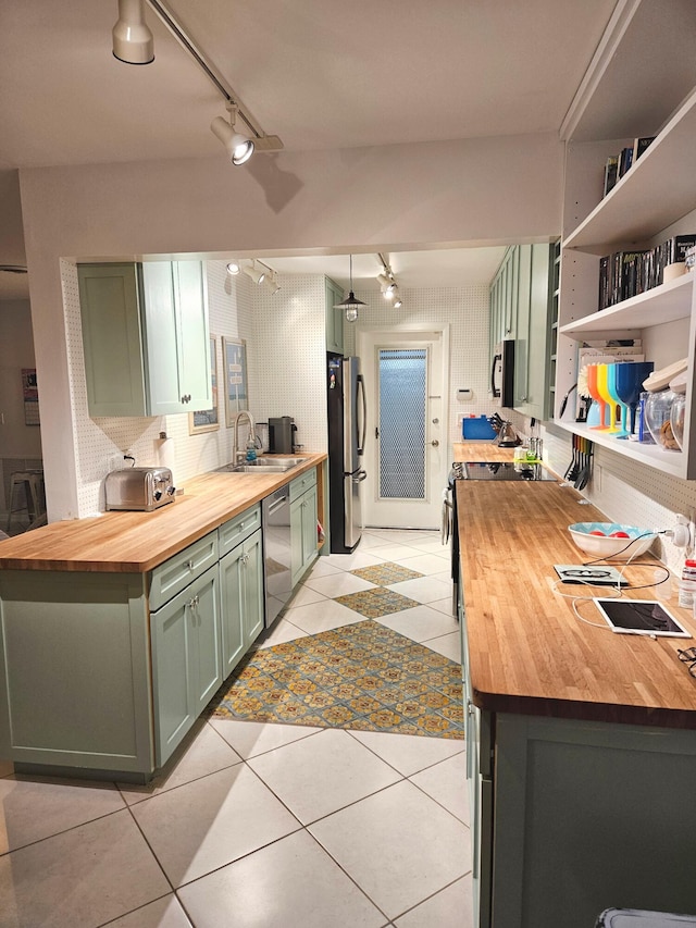 kitchen with stainless steel appliances, butcher block countertops, a sink, tasteful backsplash, and green cabinetry