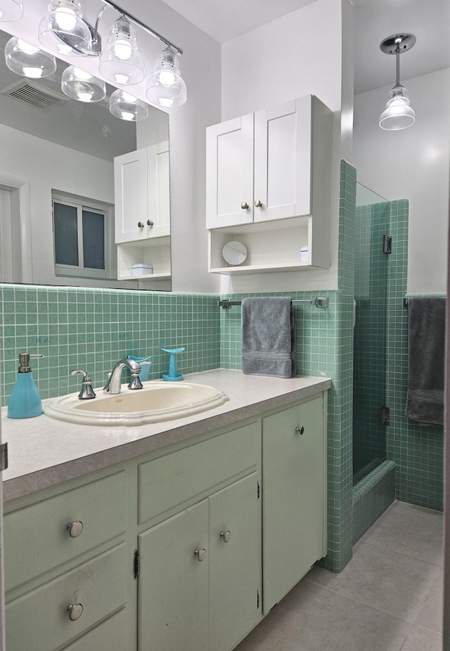 bathroom with a stall shower, vanity, tile walls, and tile patterned floors