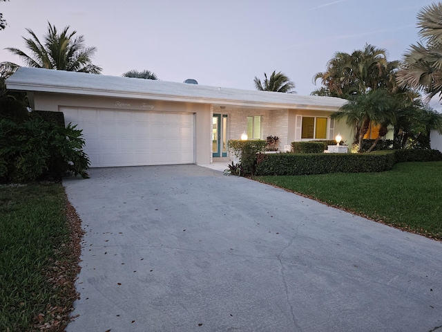 single story home with a garage, a lawn, and concrete driveway