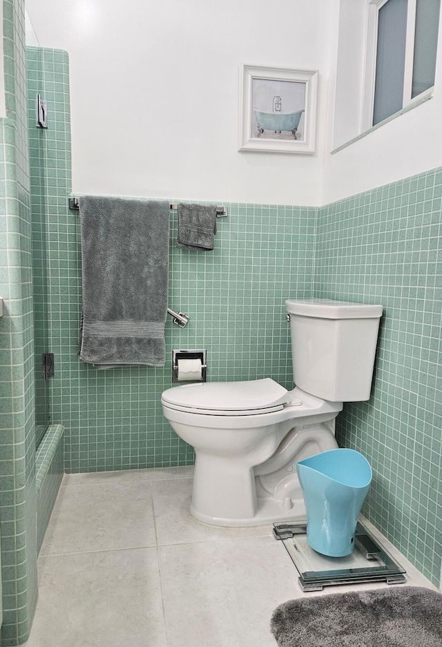 bathroom featuring tile patterned flooring, wainscoting, tile walls, and toilet