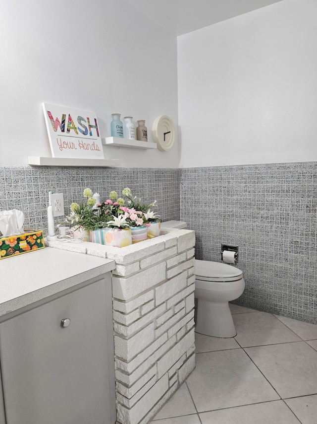 bathroom with toilet, wainscoting, tile walls, and tile patterned floors