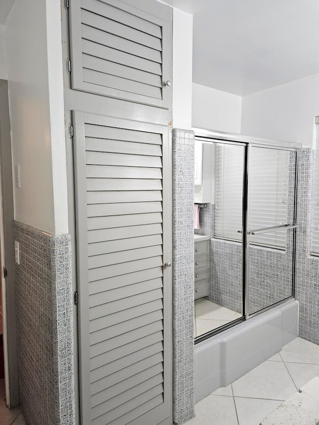 full bath featuring tile patterned flooring and bath / shower combo with glass door