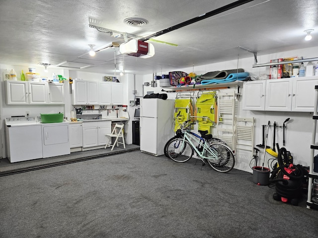 garage featuring washing machine and dryer, visible vents, a garage door opener, and freestanding refrigerator