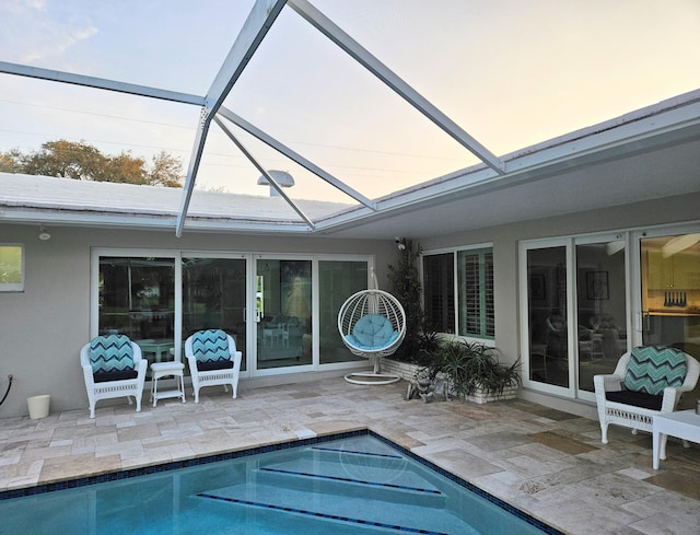 pool at dusk with a patio area, glass enclosure, and an outdoor pool