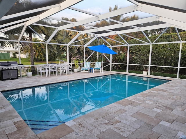 outdoor pool featuring a patio area, glass enclosure, and area for grilling