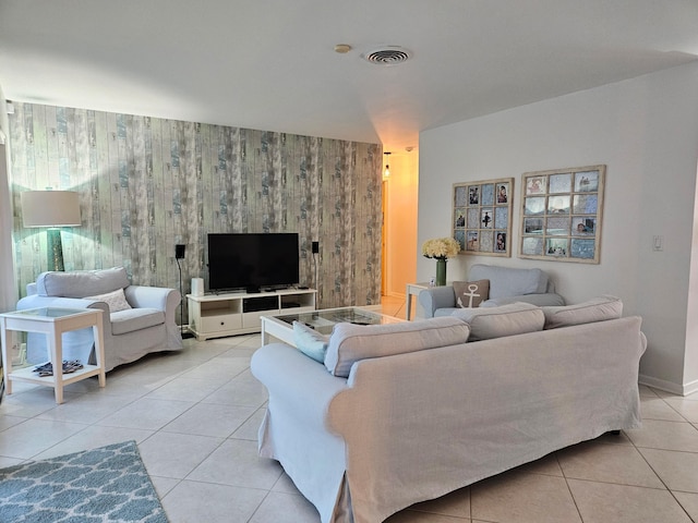 living area featuring light tile patterned floors, an accent wall, visible vents, and baseboards