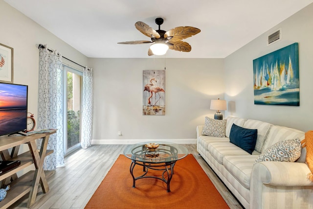 living area featuring a ceiling fan, visible vents, baseboards, and wood finished floors