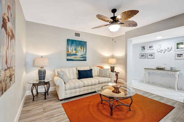 living area with light wood-style floors, visible vents, ceiling fan, and baseboards