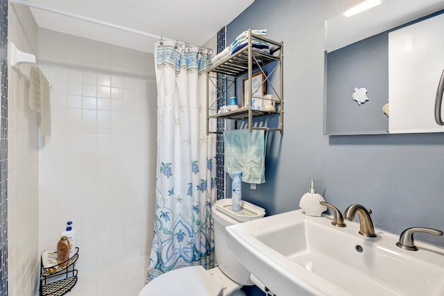 full bathroom featuring tiled shower, a sink, and toilet