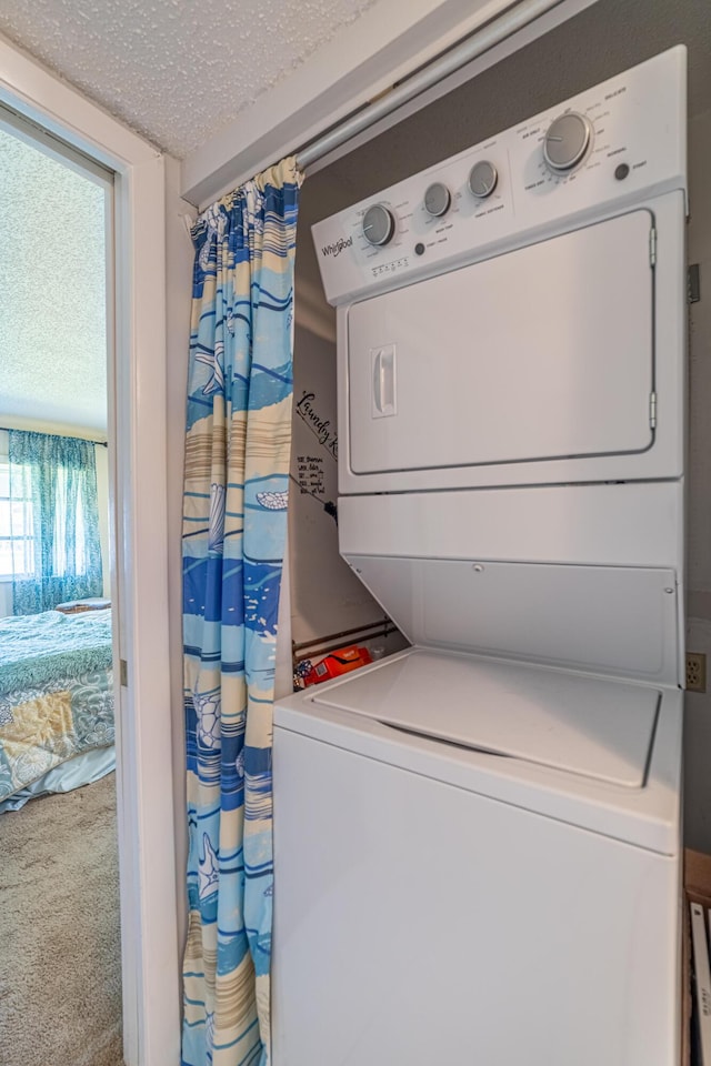 clothes washing area featuring stacked washer / dryer, a textured ceiling, and carpet