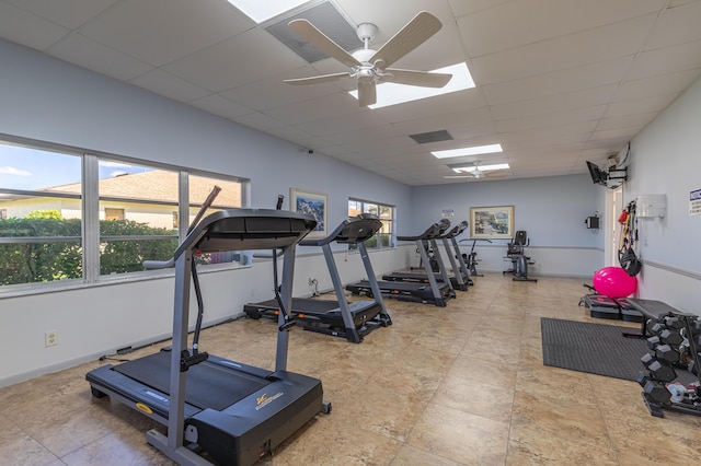 workout area featuring a drop ceiling, a ceiling fan, and a healthy amount of sunlight