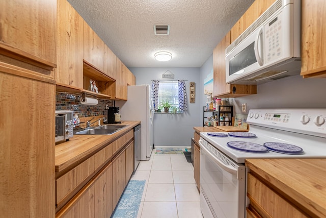 kitchen with white appliances, butcher block counters, visible vents, and a sink