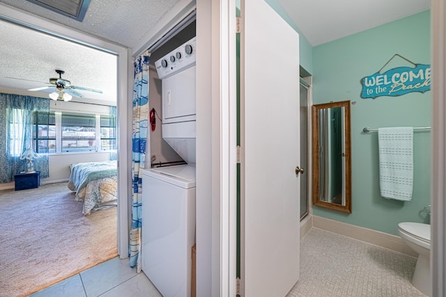 clothes washing area with a textured ceiling, ceiling fan, carpet floors, laundry area, and stacked washing maching and dryer