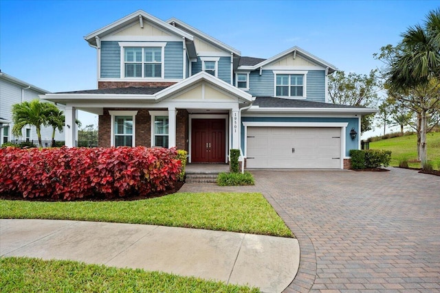 craftsman inspired home featuring an attached garage, covered porch, decorative driveway, board and batten siding, and brick siding