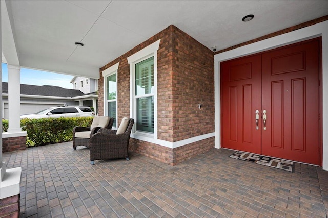 doorway to property featuring a porch and brick siding