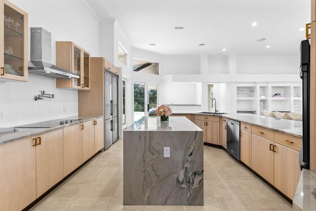 kitchen with wall chimney exhaust hood, a large island, light stone counters, glass insert cabinets, and a sink